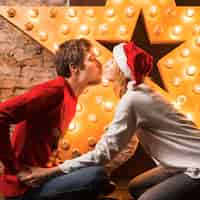 Foto grátis casal se beijando na frente da decoração das estrelas de natal