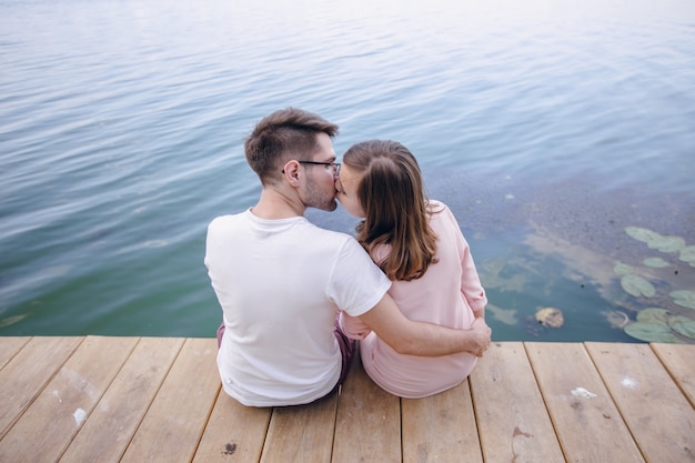 Casal se beijando sentado em um píer de madeira