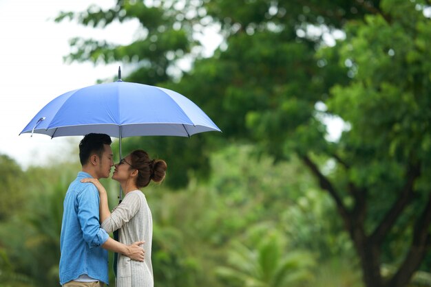 Casal se beijando sob o guarda-chuva