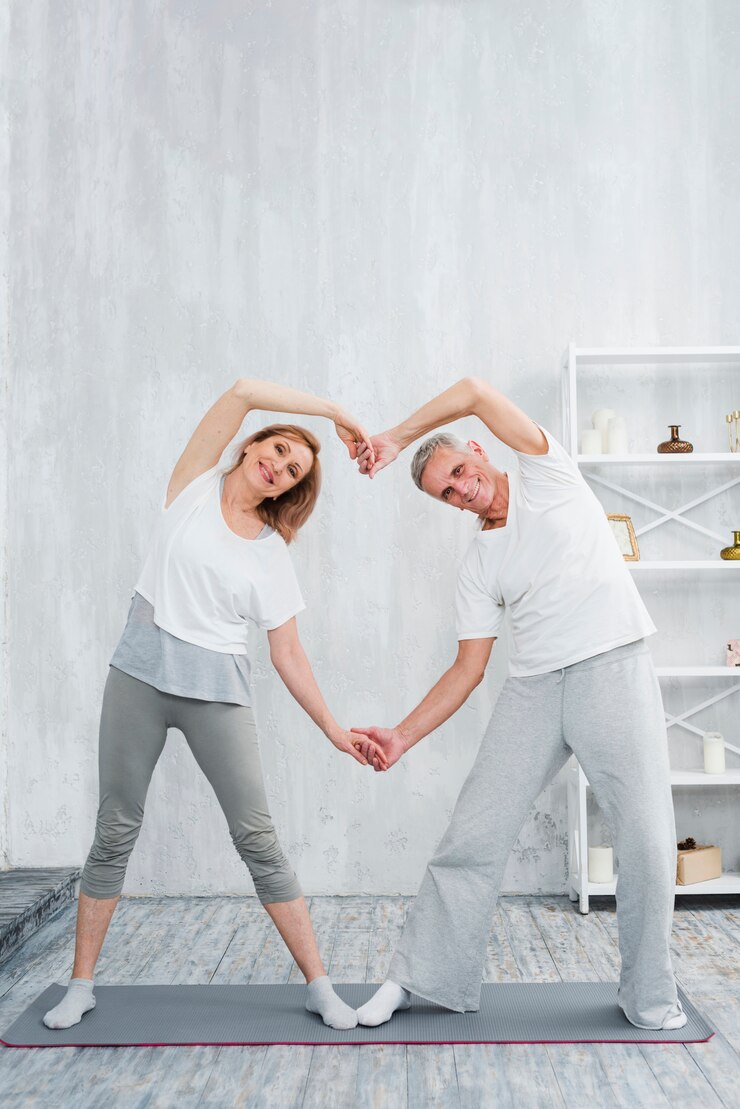 Foto grátis casal sênior alegre fazendo formato de coração com as mãos durante o exercício em casa