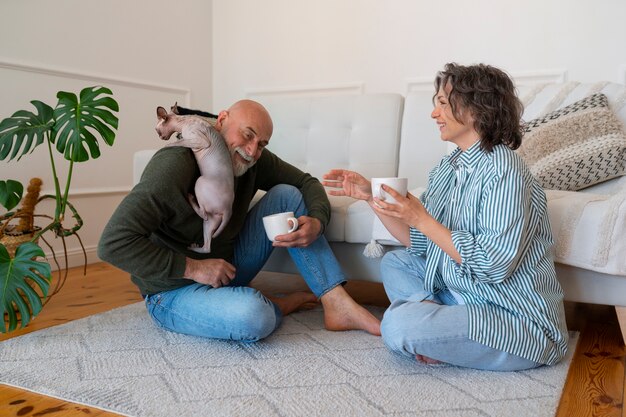 Casal sênior de tiro completo com gato em casa