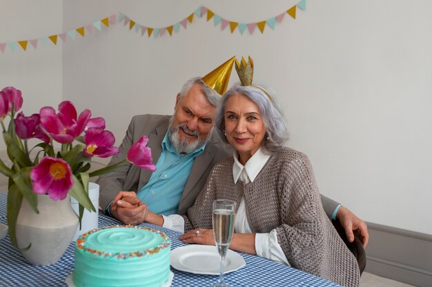 Casal sênior de tiro médio comemorando com bolo