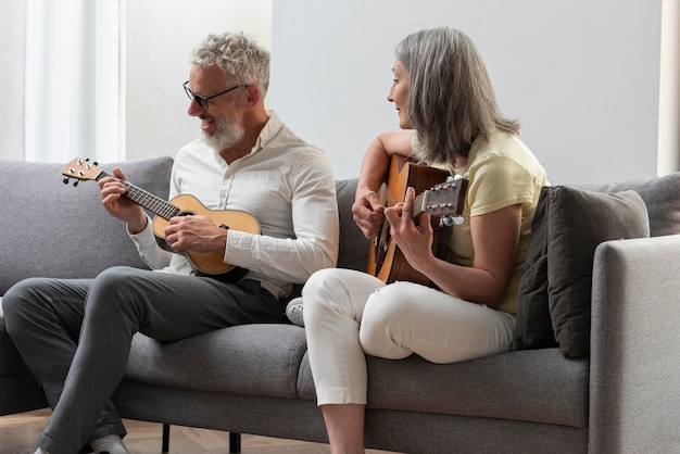 Casal sênior em casa estudando aulas de violão e ukulele no laptop