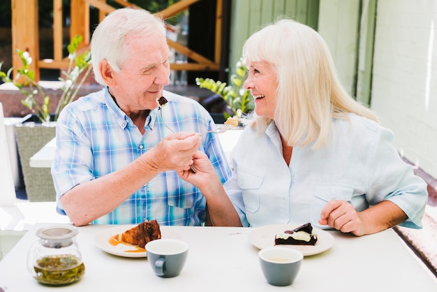 Casal sênior romântico sentado no café no terraço e apreciar bolos