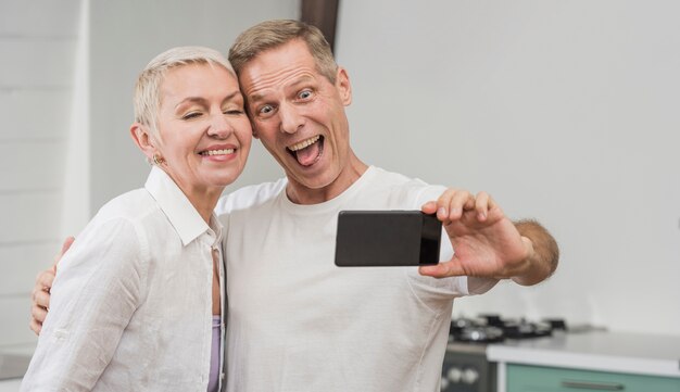 Casal sênior tomando uma selfie dentro de casa