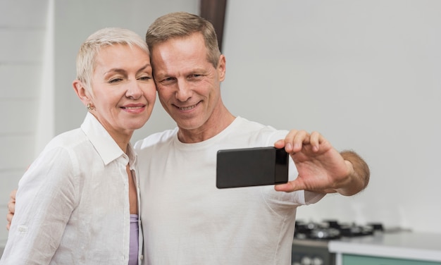 Casal sênior tomando uma selfie em casa