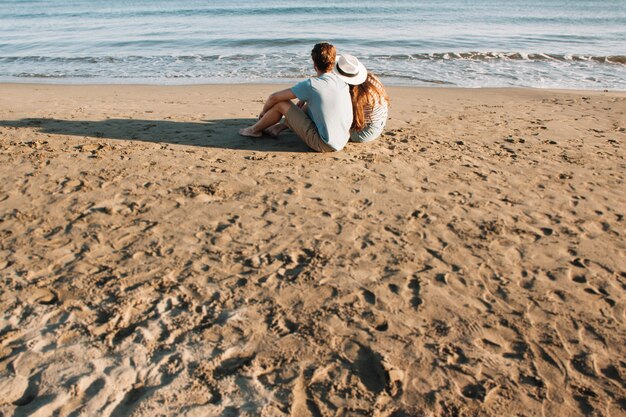 Casal sentado ao lado da vista traseira do mar