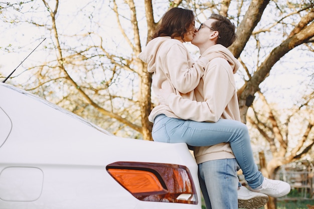 Foto grátis casal sentado em um capô de carro em um parque
