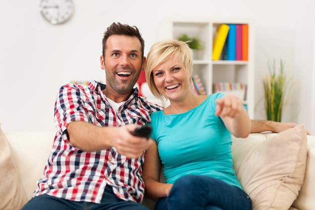 Casal sentado no sofá assistindo filme engraçado