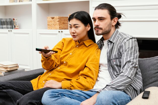 Casal sentado no sofá assistindo tv e ficando junto