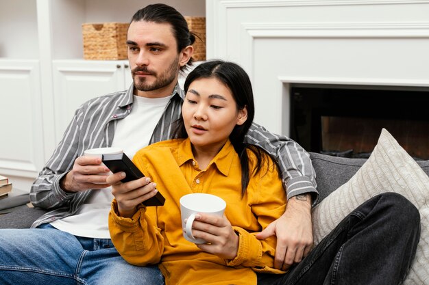 Casal sentado no sofá assistindo tv