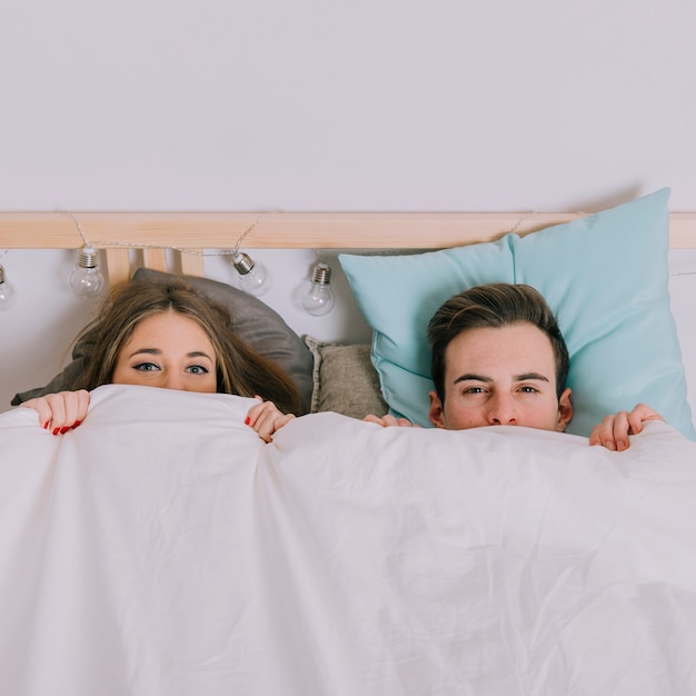 Foto grátis casal sob o cobertor olhando a câmera