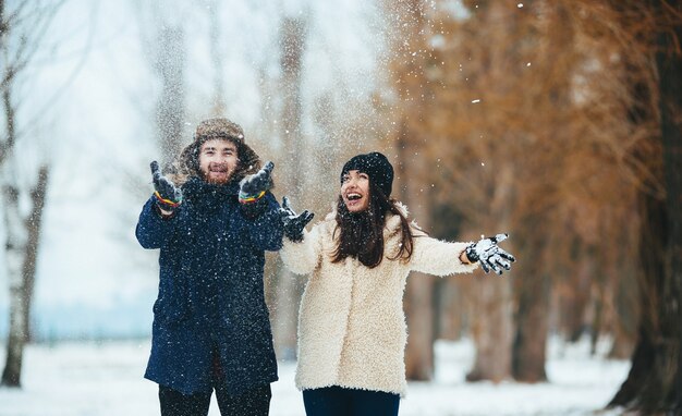 Casal sorridente brincando com neve