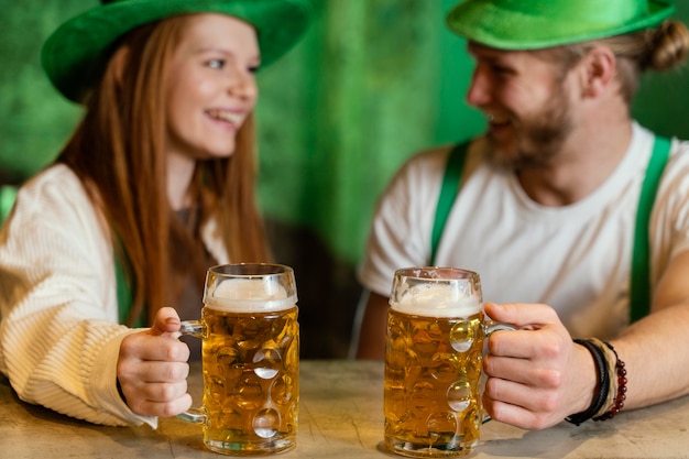 Foto grátis casal sorridente celebrando st. dia de patrick com bebidas no bar