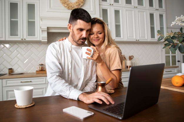 Casal sorridente com foto média e laptop