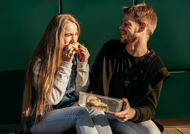 Casal sorridente comendo juntos ao ar livre