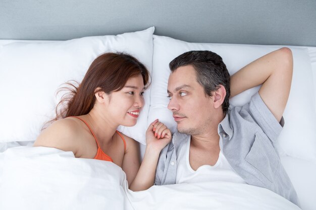 Casal sorridente conversando e deitado na cama