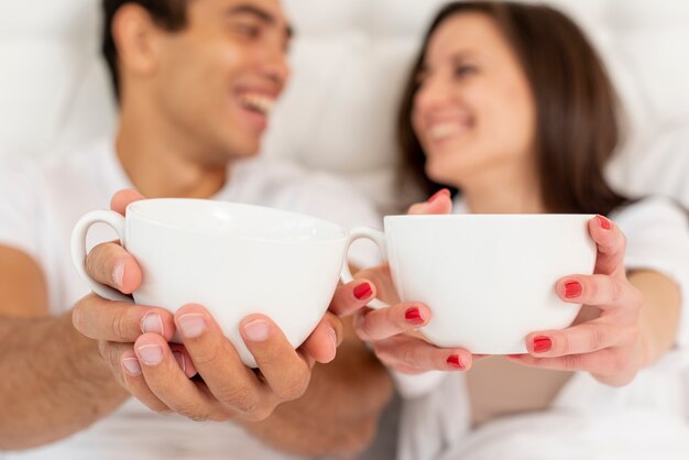 Casal sorridente de close-up com copos de café