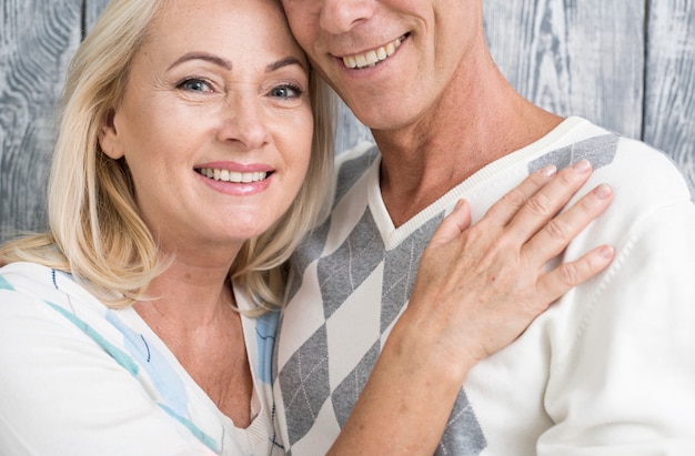 Casal sorridente de close-up com fundo de madeira