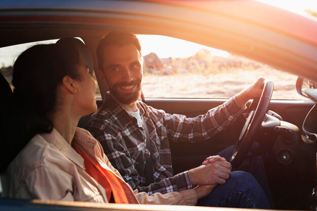 Casal sorridente de lado viajando de carro