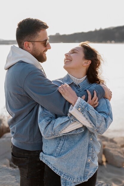 Casal sorridente de tiro médio à beira-mar