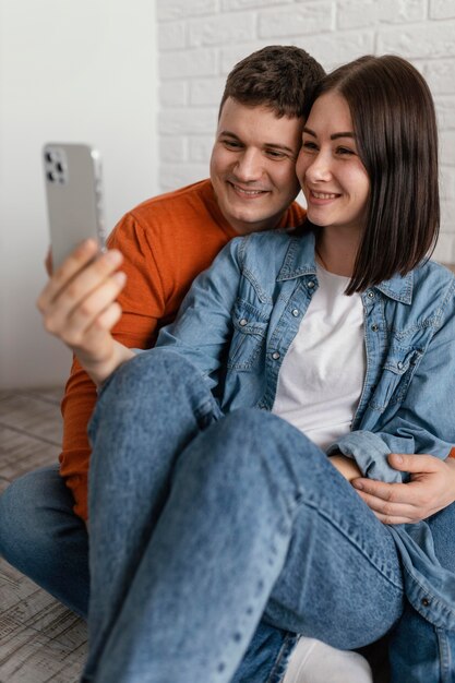 Casal sorridente de tiro médio com smartphone