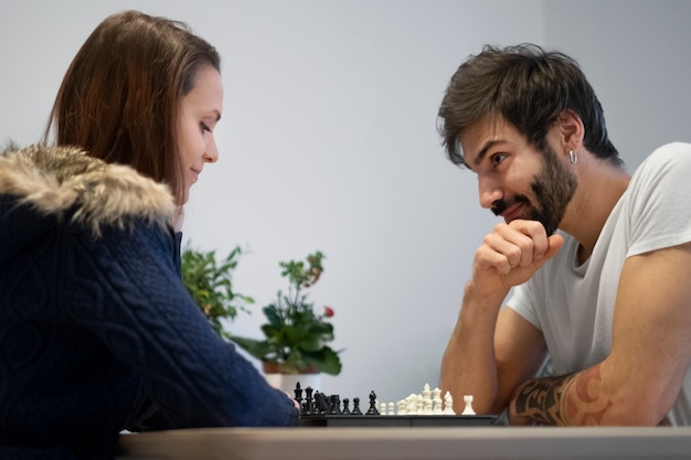 Foto grátis casal sorridente de tiro médio jogando xadrez