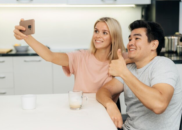 Casal sorridente em casa durante a pandemia tirando uma selfie com o smartphone