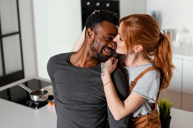 Casal sorridente em foto média dentro de casa