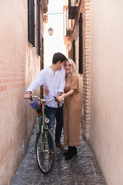 Casal sorridente posando ao ar livre com bicicleta