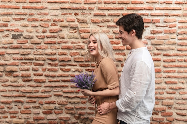 Casal sorridente posando enquanto segura o buquê de flores de lavanda