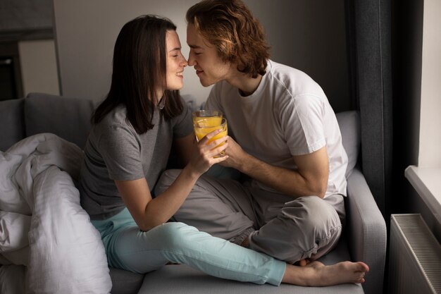 Casal sorridente segurando copo de suco de laranja