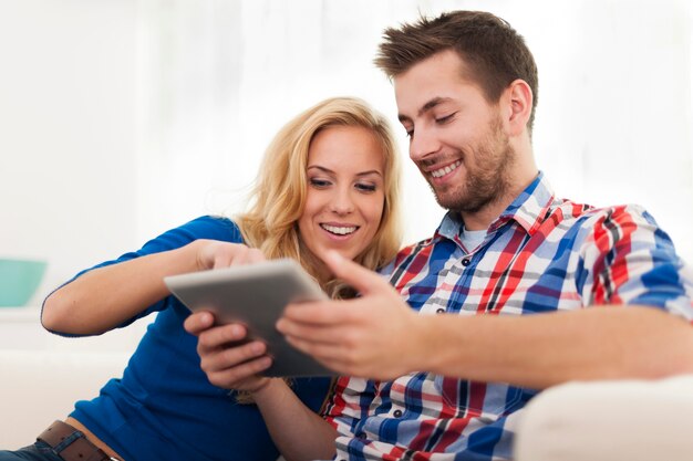 Casal sorridente usando tablet digital em casa
