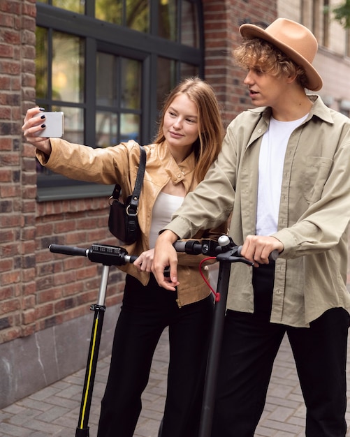 Casal tirando selfie com scooters ao ar livre