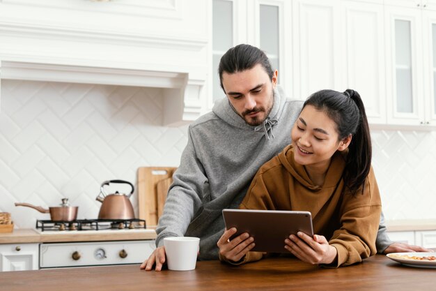 Casal tomando café da manhã na cozinha e usando um tablet