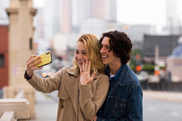 Casal tomando selfie juntos ao ar livre com anel de noivado