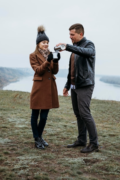 Casal tomando uma bebida quente ao ar livre