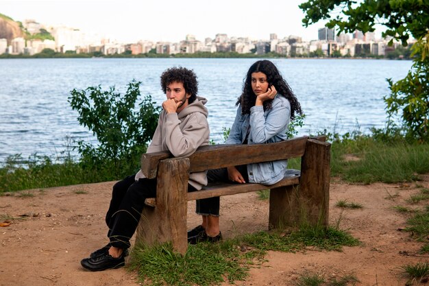Casal triste sentado no banco à beira do lago