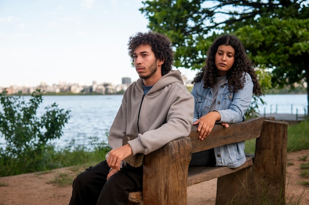 Casal triste sentado no banco à beira do lago