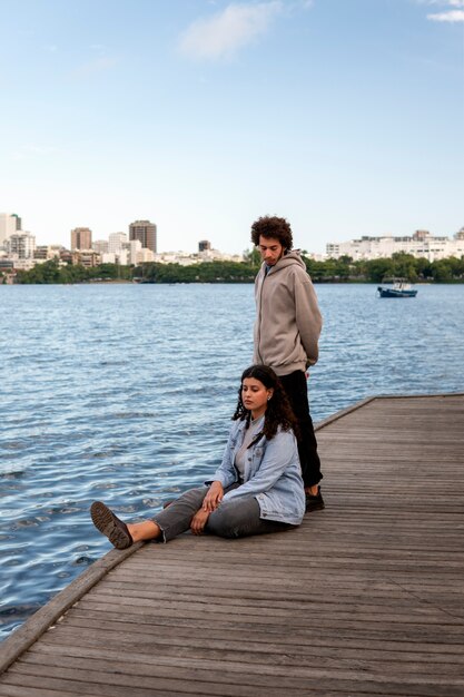 Casal triste sentado no cais ao lado do lago