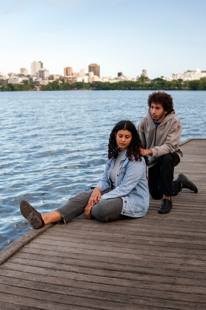 Casal triste sentado no cais ao lado do lago