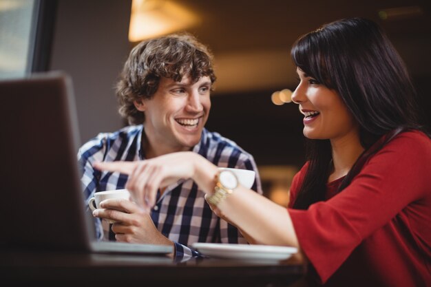 Casal usando laptop enquanto toma café