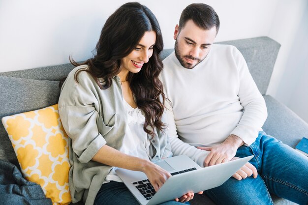 Casal usando laptop no sofá