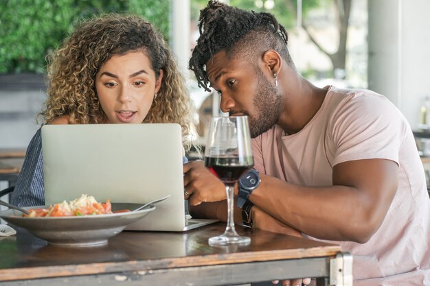 Casal usando um laptop enquanto almoçavam juntos.