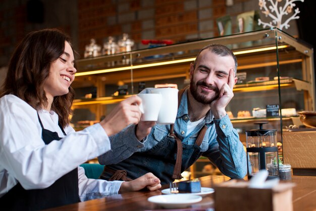 Casal vestindo aventais tomando café na loja