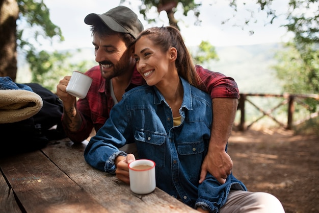 Foto grátis casal viajando na natureza e desfrutando de uma bebida