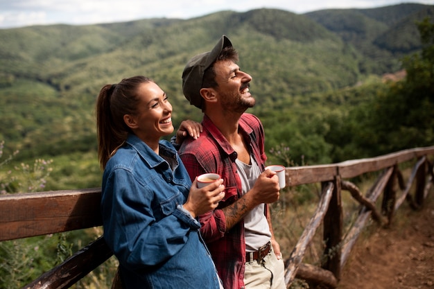 Casal viajando na natureza e desfrutando de uma bebida