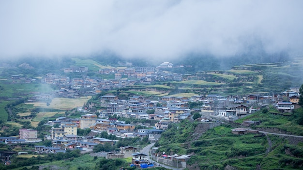 Casas de uma pequena cidade cercada por florestas e uma nuvem de neblina