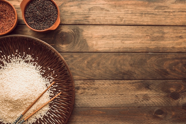 Castanho; vermelho; e grãos de arroz branco na mesa de madeira