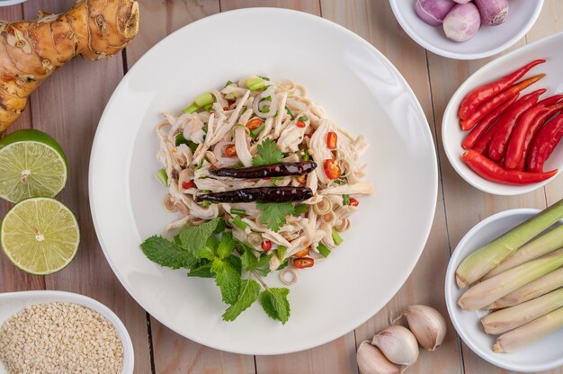 Cavala frita coberta com galanga, pimenta, hortelã, cebola vermelha em um prato branco.